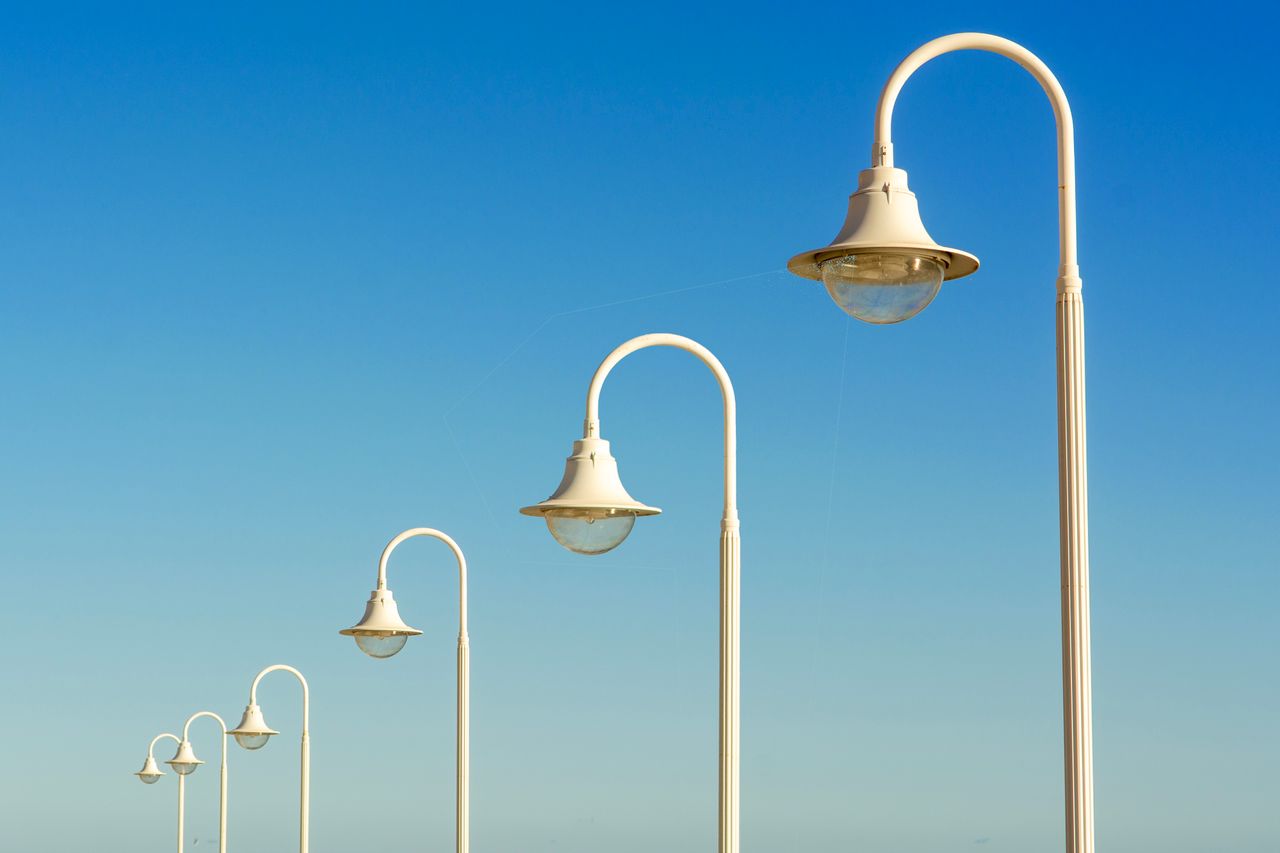 The Art of Drawing Readers In: Your attractive post title goes here White street lamps line up with diminishing perspective under a clear sky, creating a sleek and modern urban scene.