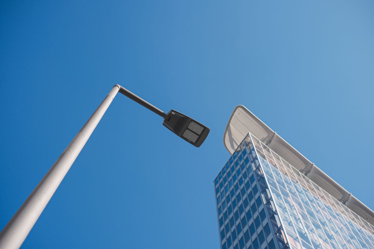 Crafting Captivating Headlines: Your awesome post title goes here A contemporary skyscraper and streetlamp set against a clear blue sky, capturing urban architectural design.