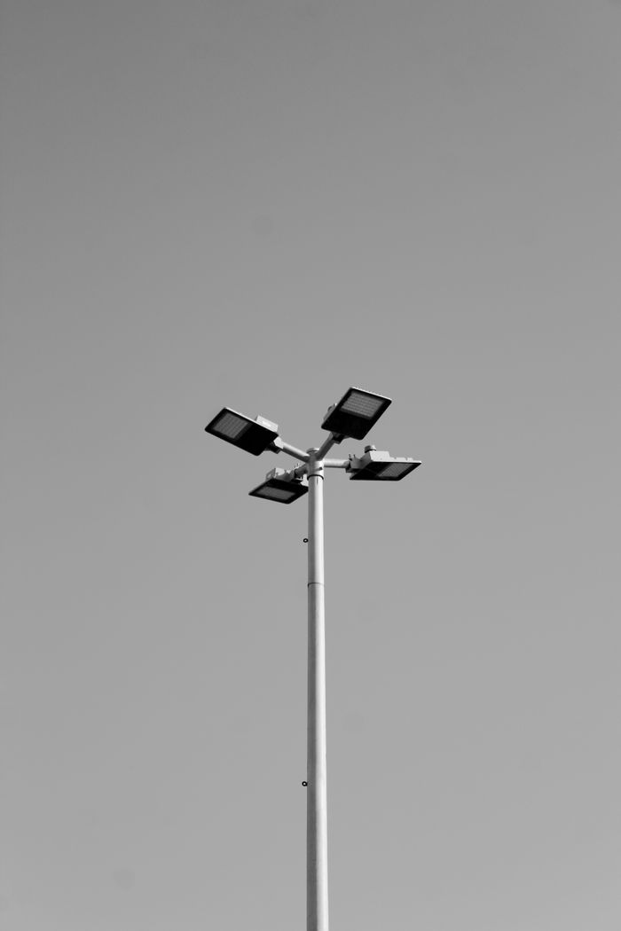 About A grayscale photo capturing the simplicity of a street light against a clear sky.